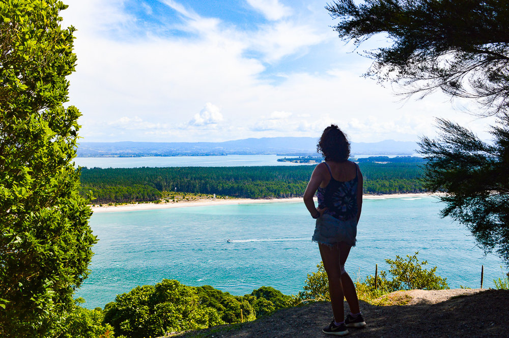 girl posing in front of sea on a hill surrounded by trees