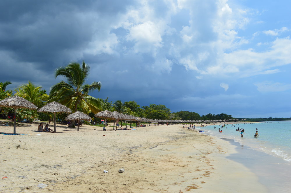 Cuban beach with palm parasols and stormy sky