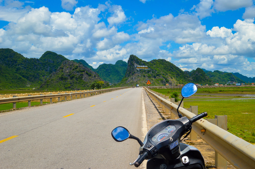 motorbike parked by side of road with mountains in the background in vietnam