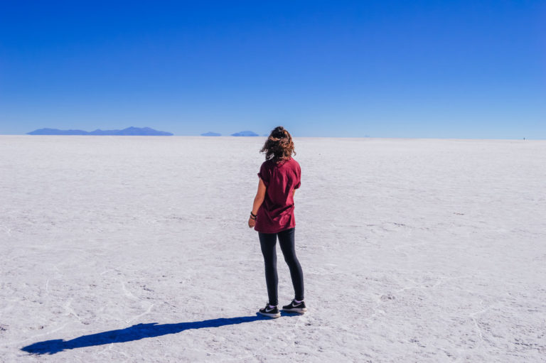 girl in red top standing on white endless salt flats